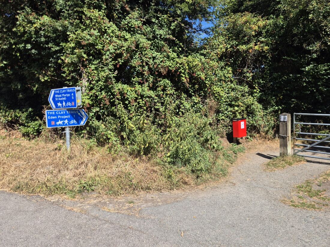New red dog-waste bin beside the Clay Trails signs and gate