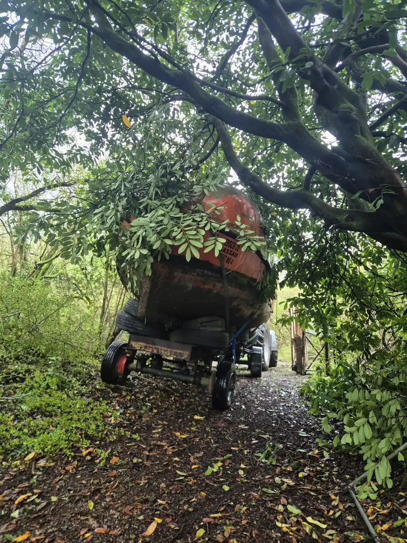 The lifeboat being guided through a narrow tree-lined lane by tractor