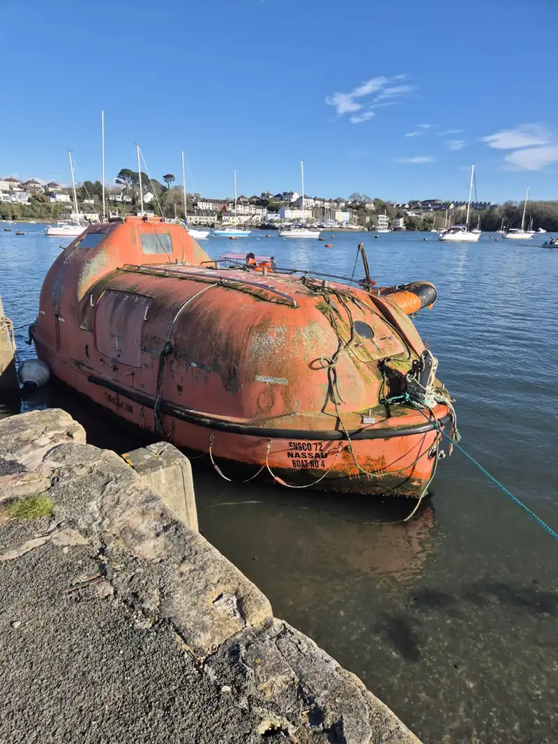 Orange enclosed survival boat on the water at Saltash